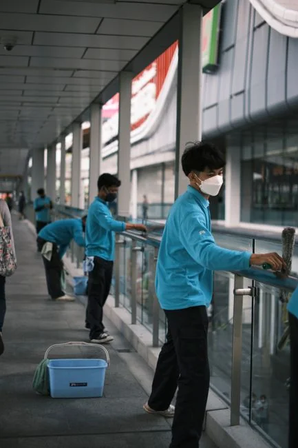 Close-up of people cleaning wooden floor with broom and dustpan indoors.